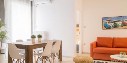 bright living room with white and orange colors with a sofa and a fridge