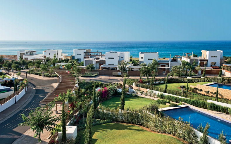 external view of complex with villas and garden with ocean inthe background